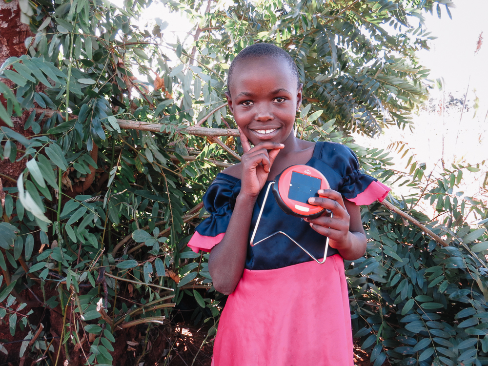 Sada, the daughter of a Solar Sister entrepreneur, poses in a photoshoot with her favorite solar lantern (S2). She tells me her favorite subjects in school are Swahili and English.