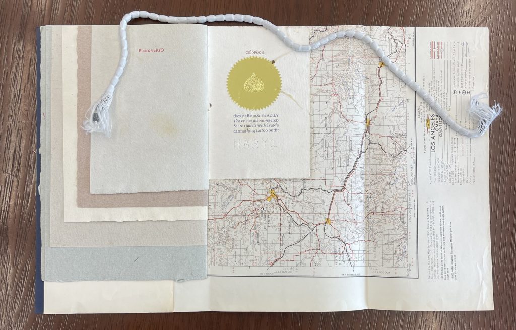 An open book with pages of varying sizes and a map. There is a good seal with text: Colophon, there are just exactly 0 copies all numbered & initialled with Ivan's earmarking tattoo outfit.