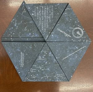 A hexagon shaped book with stars and constellations printed on it. The book opens and folds in different directions.