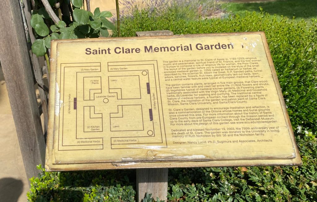 A sign depicting the layout of the Saint Clare Garden, titled "Saint Clare Memorial Garden." It also gives a brief overview on St. Claire and some of the plants in the garden.