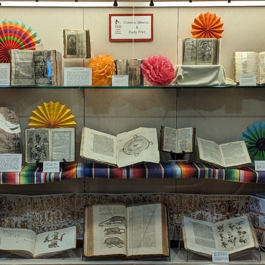 Display case with rare books and decorative paper fans from Mexico