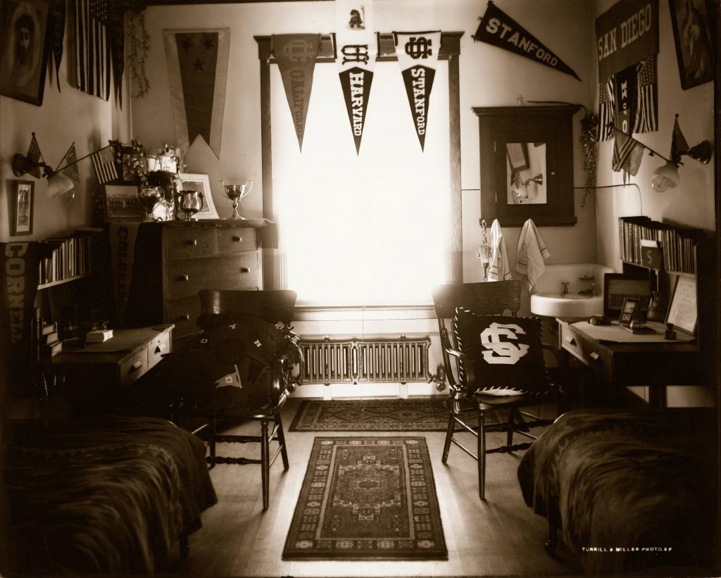 Student dormitory room decorated with pennants and trophies.