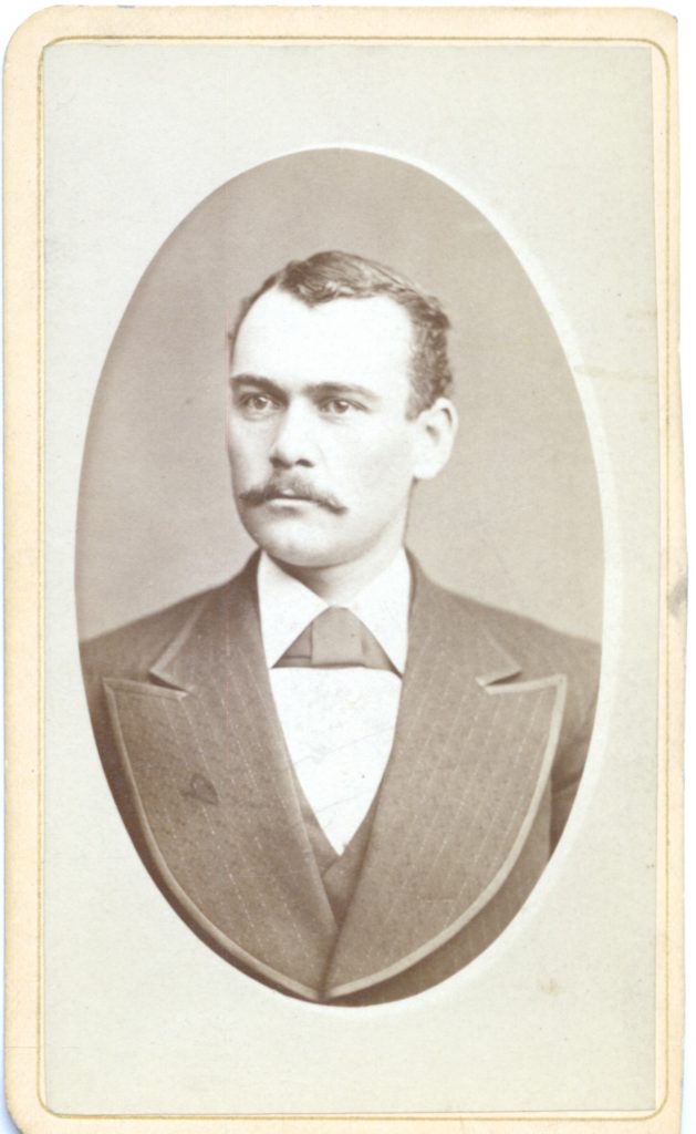 A man wearing a suit jacket and a white collared shirt.