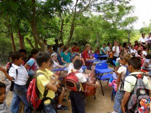 A large group of young Nicaraguan students with backpacks and American students sitting at desks outside